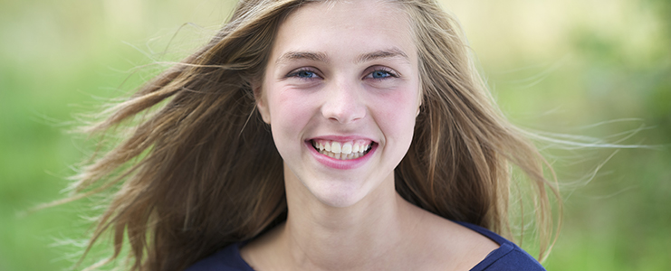 Portrait of a pretty teenage girl outside smiling